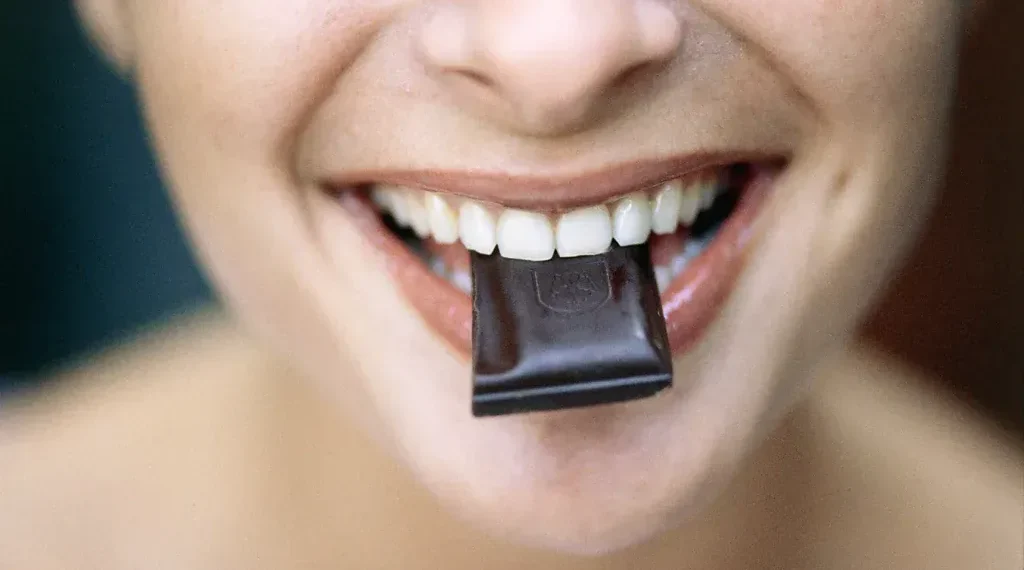 Dark chocolate bar with cocoa beans on wooden surface - Roy Morsch/Getty Images/BBC
