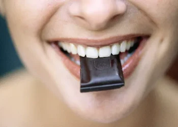 Dark chocolate bar with cocoa beans on wooden surface - Roy Morsch/Getty Images/BBC