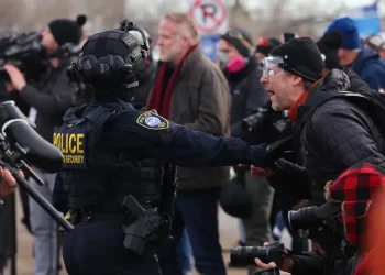 Minnesota ICE shooting scene with police vehicles and protesters - AP Photo/Adam Bettcher