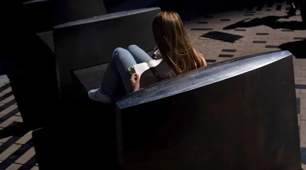 Adult reading a book in a quiet library setting - AP Photo/David Goldman, File