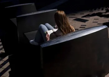 Adult reading a book in a quiet library setting - AP Photo/David Goldman, File