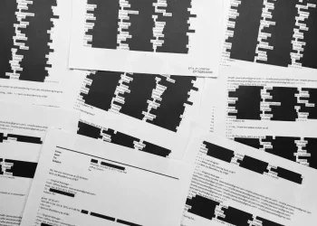 Court documents with redacted Epstein victims’ identities on a table - AP Photo/Jon Elswick