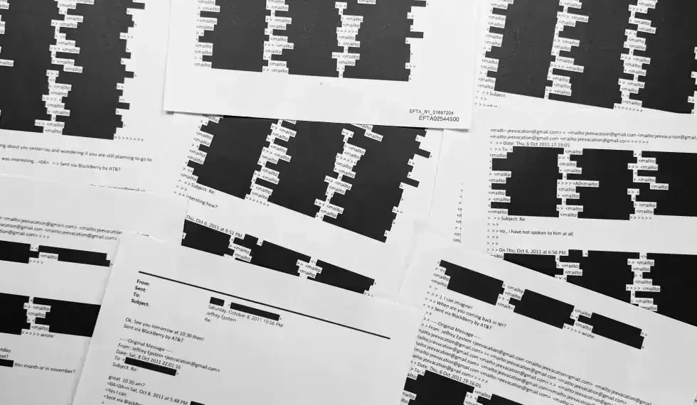 Court documents with redacted Epstein victims’ identities on a table - AP Photo/Jon Elswick