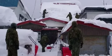 Residents walk between towering snow walls after heavy snowfall in Aomori - Photo: AFP/Japan's Ministry of Defense/Handout