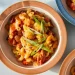 Bowl of slow cooker chili mac topped with cheese and green onions - Kristin Teig/Voracious via AP
