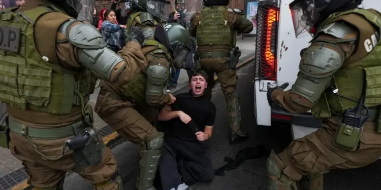 Protesters and police clash during education cuts rally in Santiago - AP Photo/Esteban Felix