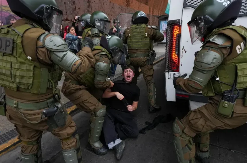 Protesters and police clash during education cuts rally in Santiago - AP Photo/Esteban Felix