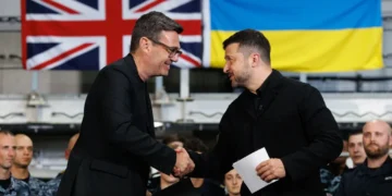 British Prime Minister Andy Burnham shakes hands with Ukrainian President Volodymyr Zelenskyy aboard HMS Queen Elizabeth in Portsmouth, with British and Ukrainian flags in the background.