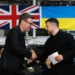 British Prime Minister Andy Burnham shakes hands with Ukrainian President Volodymyr Zelenskyy aboard HMS Queen Elizabeth in Portsmouth, with British and Ukrainian flags in the background.