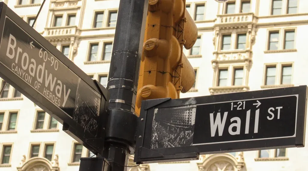 Street signs marking the intersection of Broadway and Wall Street in New York City's Financial District, a landmark associated with the U.S. financial markets.