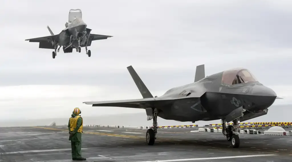Two F-35B Lightning II stealth fighter aircraft land on the flight deck of the USS America during operational testing in the Pacific Ocean.