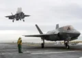 Two F-35B Lightning II stealth fighter aircraft land on the flight deck of the USS America during operational testing in the Pacific Ocean.