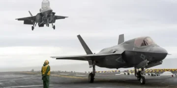 Two F-35B Lightning II stealth fighter aircraft land on the flight deck of the USS America during operational testing in the Pacific Ocean.