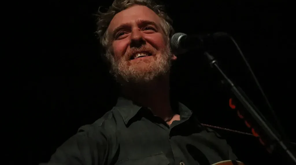 Irish singer-songwriter Glen Hansard performs on stage with an acoustic guitar during a concert at the Palace Theatre in St. Paul, Minnesota.