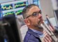 Electronic market boards display mixed global stock index performances and AI shares. - AP Photo/Richard Drew