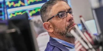 Electronic market boards display mixed global stock index performances and AI shares. - AP Photo/Richard Drew