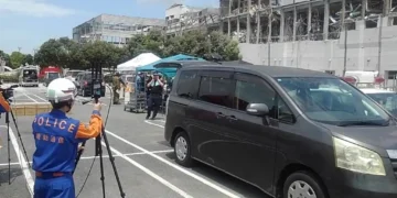 National Police Agency personnel operate emergency communications equipment during the 2026 Kumamoto earthquake response at Aeon Mall Kumamoto in Japan.