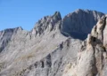 Mountain landscape in Olympus National Park, Greece, showing forested slopes, rocky peaks, and natural scenery beneath a clear sky.