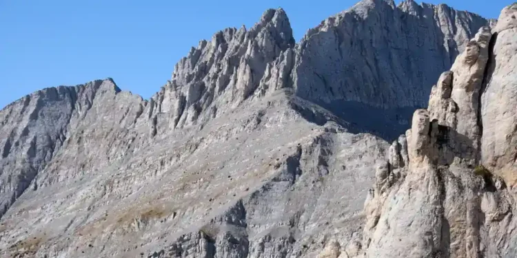 Mountain landscape in Olympus National Park, Greece, showing forested slopes, rocky peaks, and natural scenery beneath a clear sky.