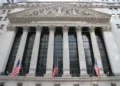 Exterior view of the New York Stock Exchange building on Wall Street in New York City's Financial District, displaying its neoclassical façade and American flags.