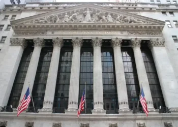 Exterior view of the New York Stock Exchange building on Wall Street in New York City's Financial District, displaying its neoclassical façade and American flags.