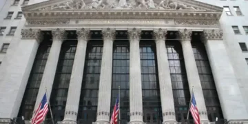 Exterior view of the New York Stock Exchange building on Wall Street in New York City's Financial District, displaying its neoclassical façade and American flags.