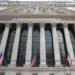 Exterior view of the New York Stock Exchange building on Wall Street in New York City's Financial District, displaying its neoclassical façade and American flags.