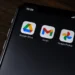 Close-up of a smartphone screen displaying the Google Drive, Gmail and Google Photos app icons against a dark background.