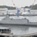 Japan Maritime Self-Defense Force frigate JS Mogami (FFM-1) moored at Yokosuka Naval Base, viewed from the left rear during a port visit.