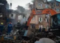Ukrainian emergency responders work among rubble beside an excavator at a heavily damaged apartment building in Kyiv.