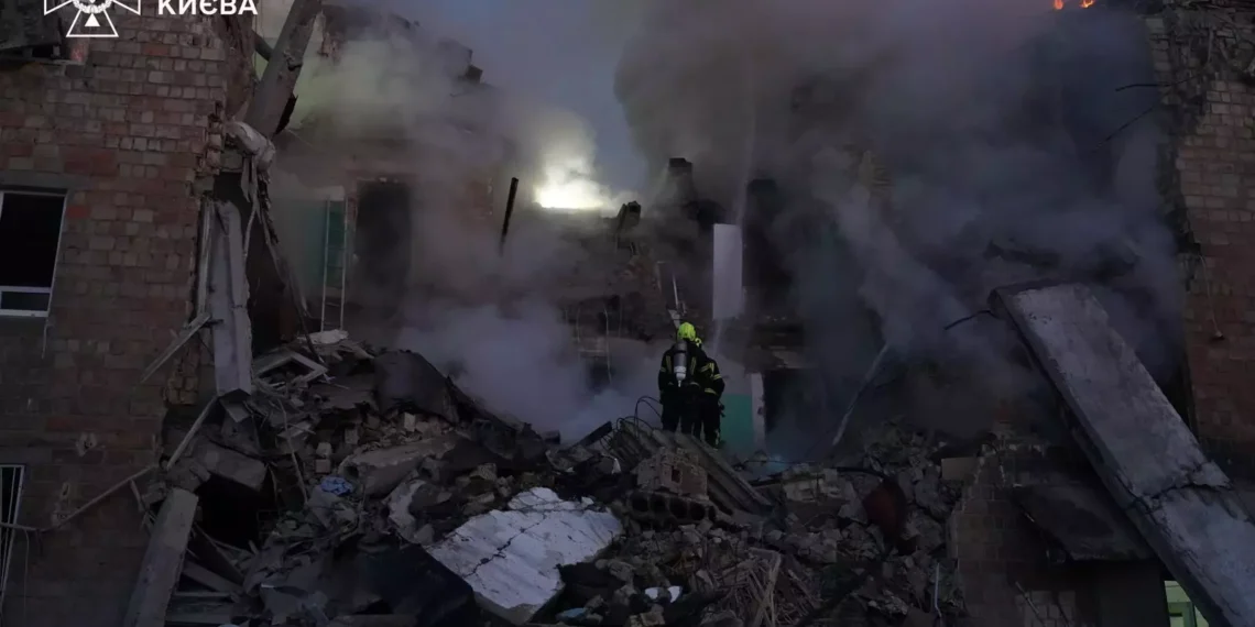 Firefighters from Ukraine's State Emergency Service work among the rubble of a severely damaged building as smoke rises following a Russian attack in Kyiv.