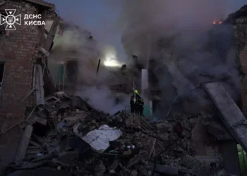 Firefighters from Ukraine's State Emergency Service work among the rubble of a severely damaged building as smoke rises following a Russian attack in Kyiv.