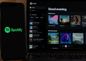 Spotify app displayed on a laptop beside a mobile phone showing the Spotify logo on a dark desktop setting.