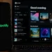 Spotify app displayed on a laptop beside a mobile phone showing the Spotify logo on a dark desktop setting.
