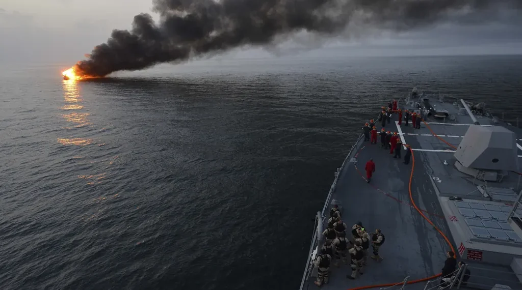 U.S. Navy sailors aboard USS William P. Lawrence prepare to provide rescue assistance to a burning vessel while transiting the Strait of Hormuz.