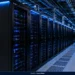Data center interior showing rows of server racks with illuminated equipment, overhead infrastructure and a cooled technical floor.