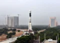 GSLV-F08 rocket stands on a mobile launch pedestal with the Vehicle Assembly Building visible behind it at an ISRO launch complex.