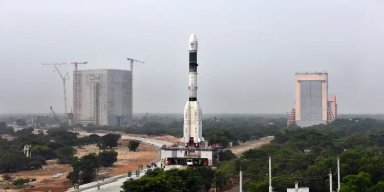 GSLV-F08 rocket stands on a mobile launch pedestal with the Vehicle Assembly Building visible behind it at an ISRO launch complex.