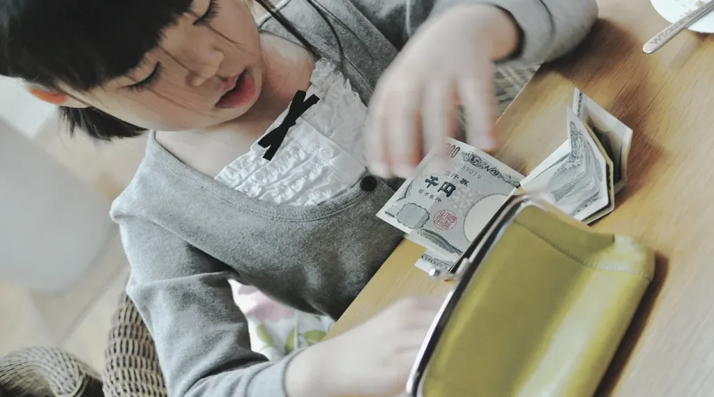 Child in Japan counting money received as New Year’s gift at home in Sapporo, Hokkaido.