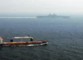 Merchant ship sails alongside USS Kearsarge while the U.S. amphibious assault ship transits the Strait of Hormuz.