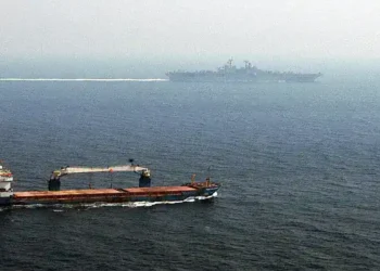 Merchant ship sails alongside USS Kearsarge while the U.S. amphibious assault ship transits the Strait of Hormuz.