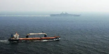 Merchant ship sails alongside USS Kearsarge while the U.S. amphibious assault ship transits the Strait of Hormuz.