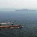 Merchant ship sails alongside USS Kearsarge while the U.S. amphibious assault ship transits the Strait of Hormuz.