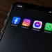 A smartphone displays Facebook, Instagram, Messenger and WhatsApp apps on its screen in a close-up original photograph.