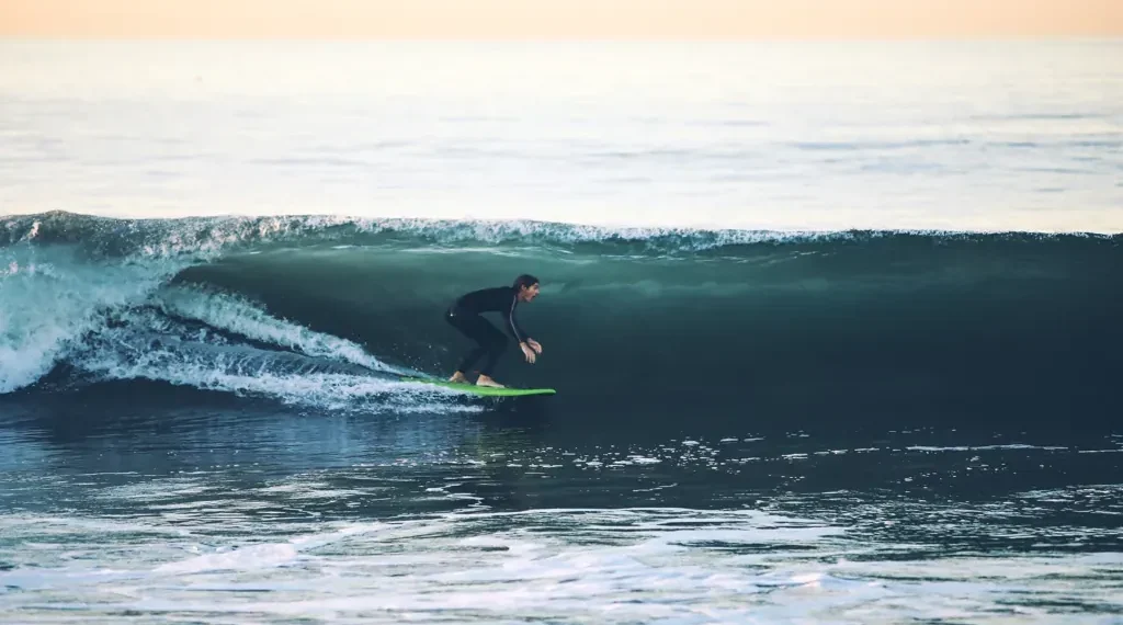 Surfer rides a large ocean wave at 54th Street in Newport Beach, California, with breaking whitewater surrounding the surfer.