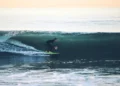 Surfer rides a large ocean wave at 54th Street in Newport Beach, California, with breaking whitewater surrounding the surfer.