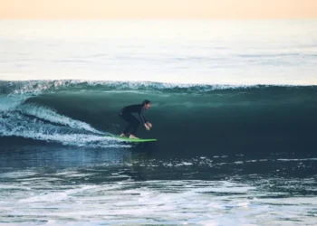 Surfer rides a large ocean wave at 54th Street in Newport Beach, California, with breaking whitewater surrounding the surfer.