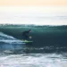 Surfer rides a large ocean wave at 54th Street in Newport Beach, California, with breaking whitewater surrounding the surfer.