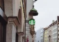 Starbucks siren sign stands before an Archangel Michael statue on Sendlinger Straße in Munich, Germany.