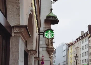 Starbucks siren sign stands before an Archangel Michael statue on Sendlinger Straße in Munich, Germany.